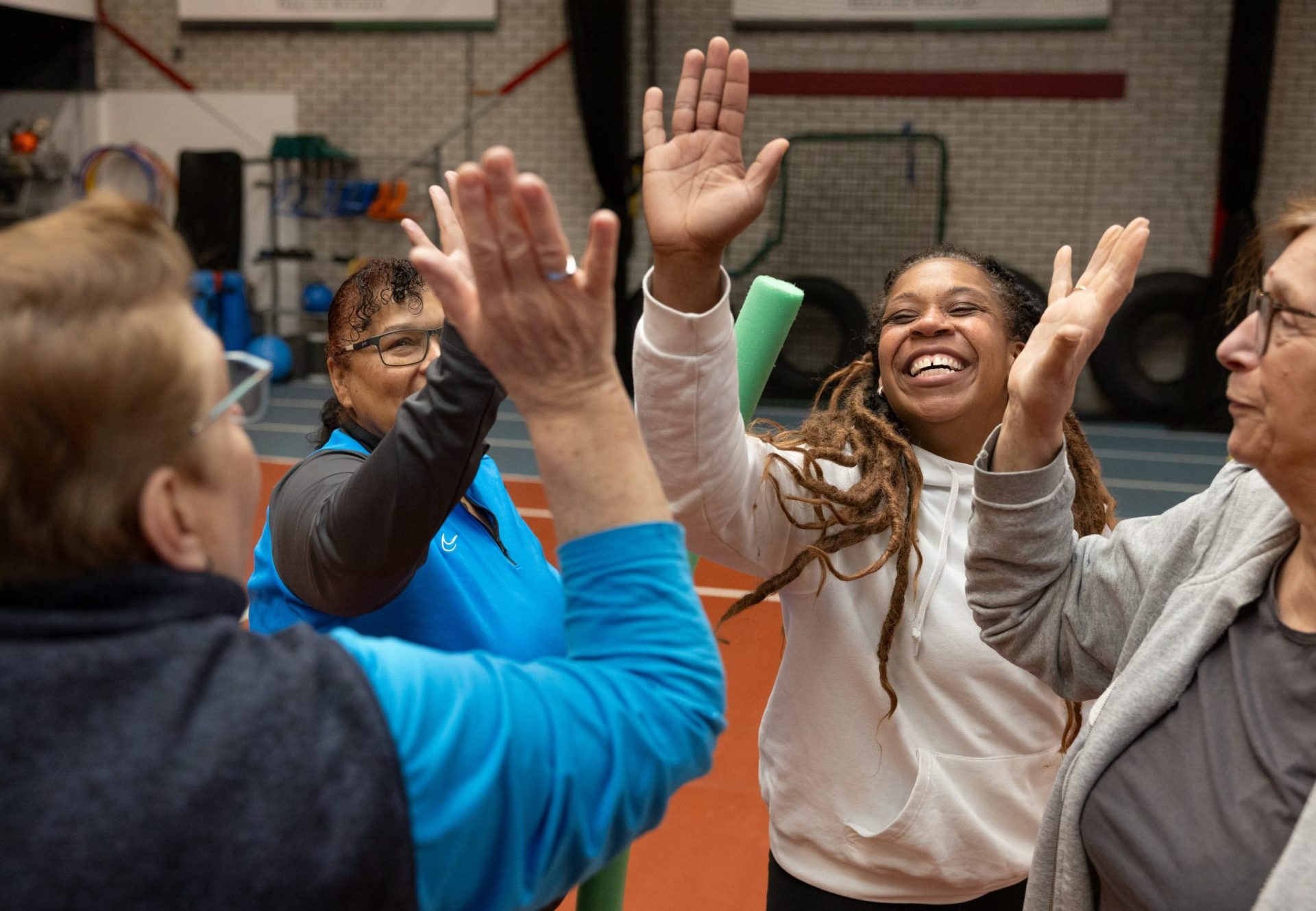 Groep deelnemers geeft elkaar lachend high five tijdens training in de sportschool