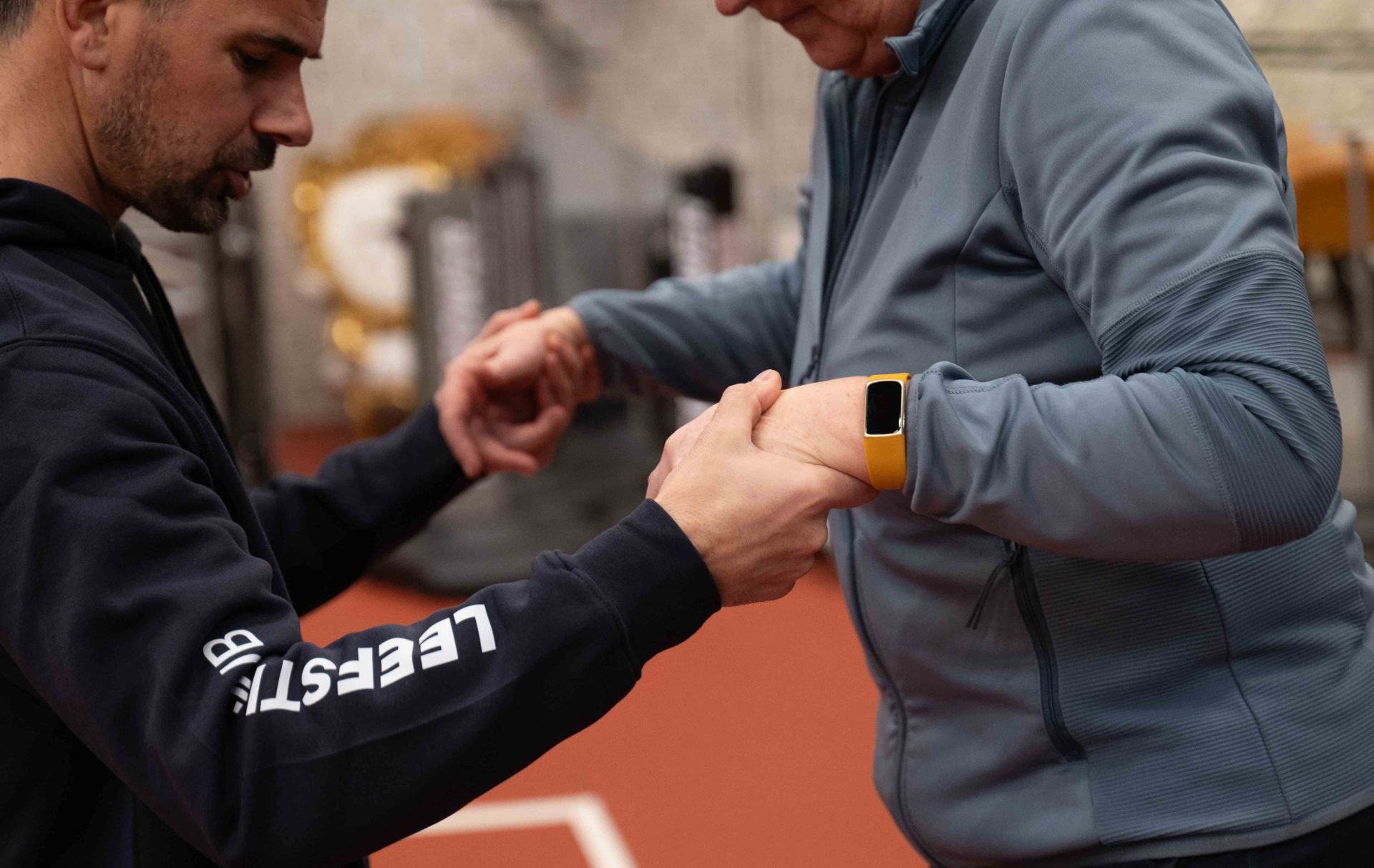 Coach controleert hartslag van deelnemer via smartwatch tijdens training