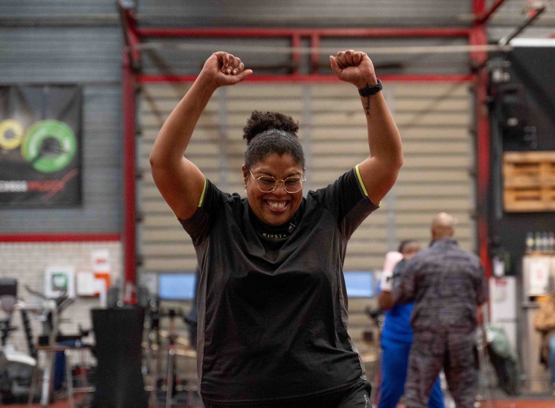 Vrouw viert overwinning met beide vingers omhoog na training in de sportschool, glimlachend in sportkleding